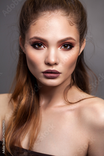 Beautiful young model with evening makeup and sharp cheekbones. Red smoky eyes and matt lips.