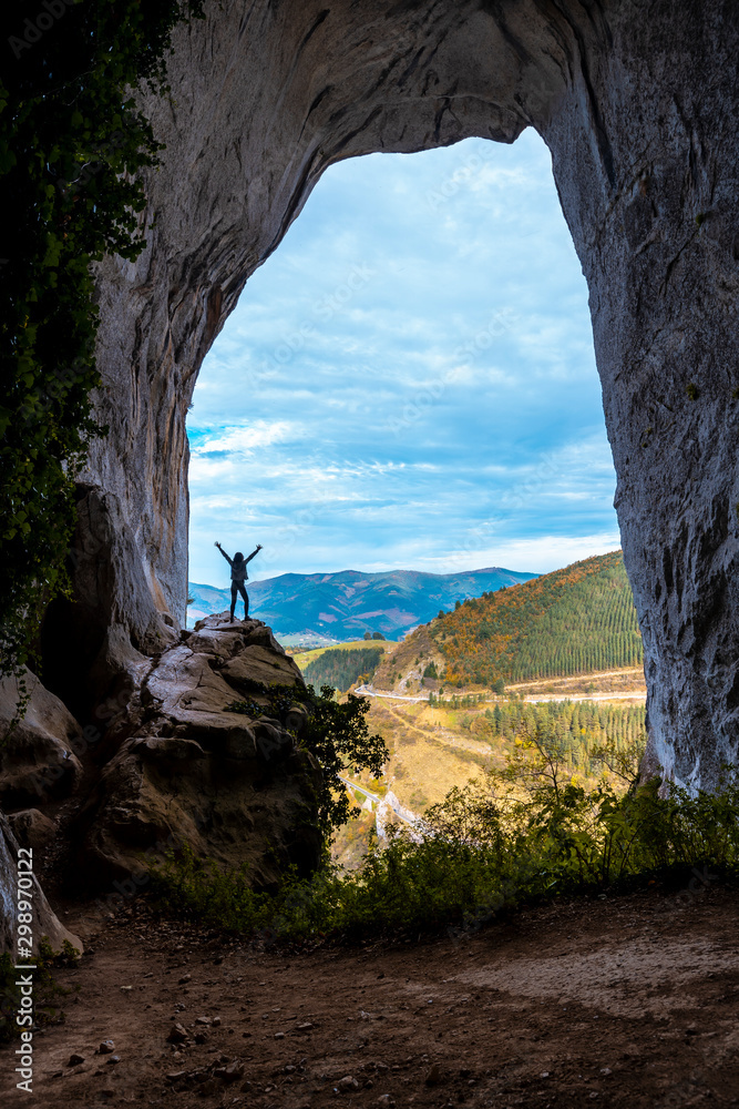 Oñati, Gipuzkoa / Spain »; October 27, 2019: A young woman in The Caves of Ojo de Aitzulo in Oñati with one arm raised