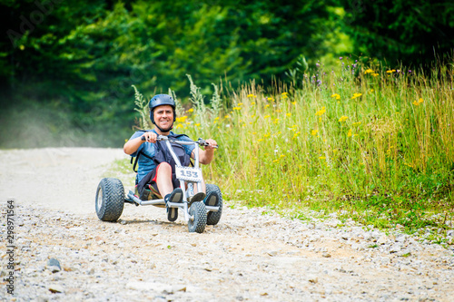 Foto Man enjoying a fast ride go kart downhill in a mountain off road.
