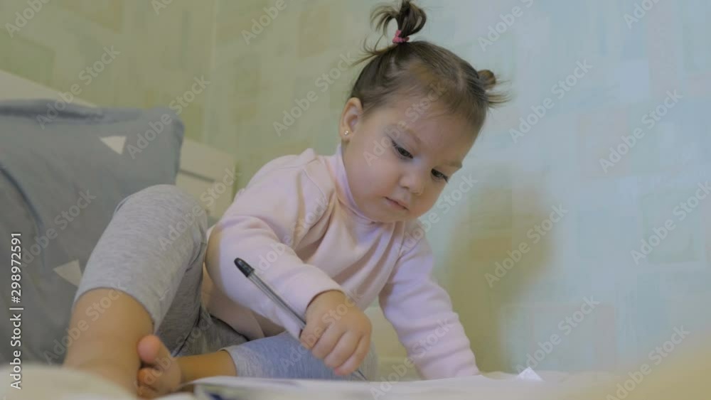 Cute little girl drawing while lying on bed at home Cute little girl drawing while lying on bed at home