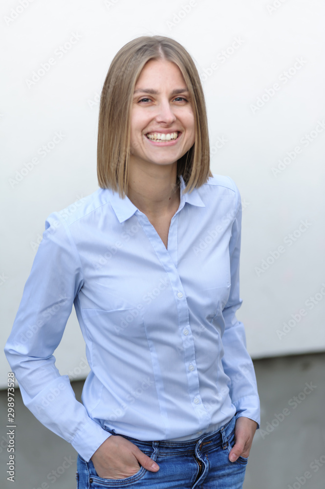 Blonde bussiness woman dressed casual with a perfect smile, standing near a white wall Blonde bussiness woman dressed casual with a perfect smile, standing near a white wall