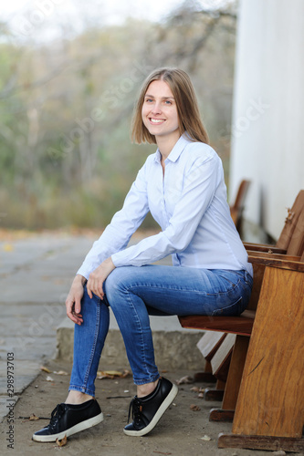 Portrait of a young smiling woman wearing casual sitting on a chair outdoor