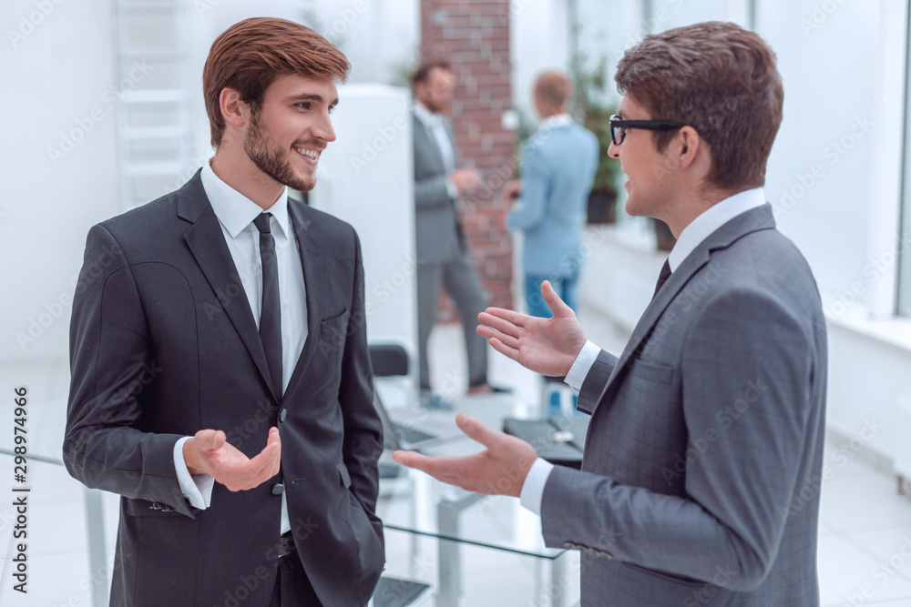 two young entrepreneurs talking standing in the office. two young entrepreneurs talking standing in the office.