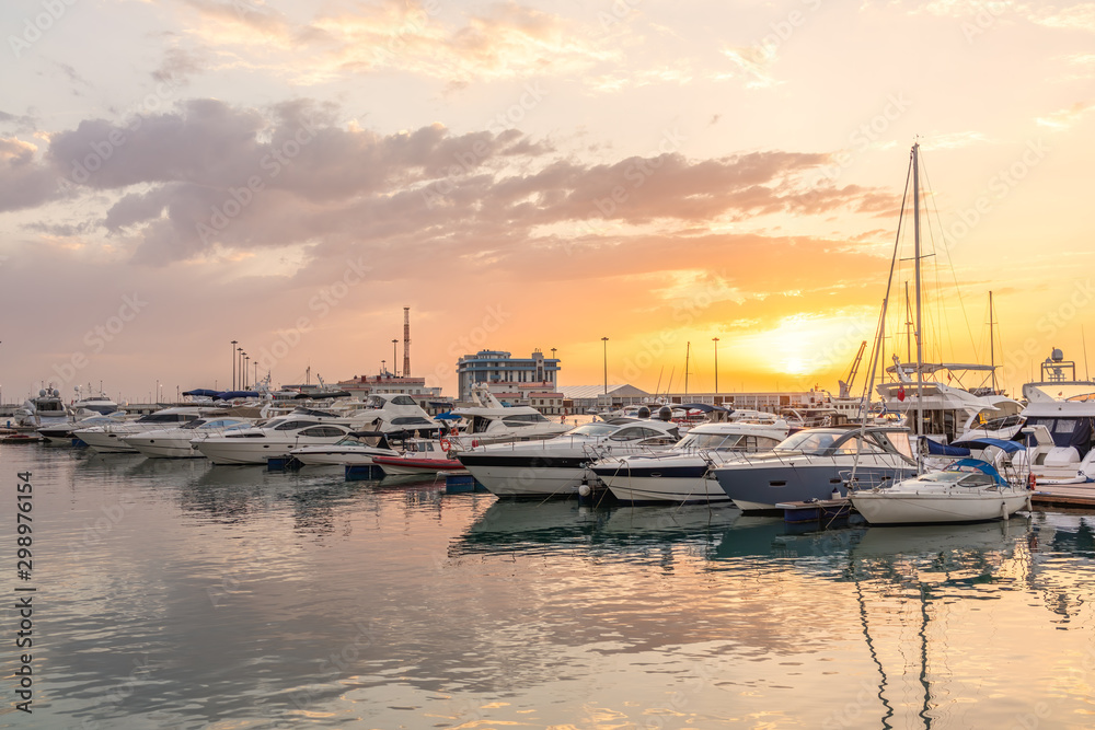 Yellow sunset in the sea harbor with moored yachts.