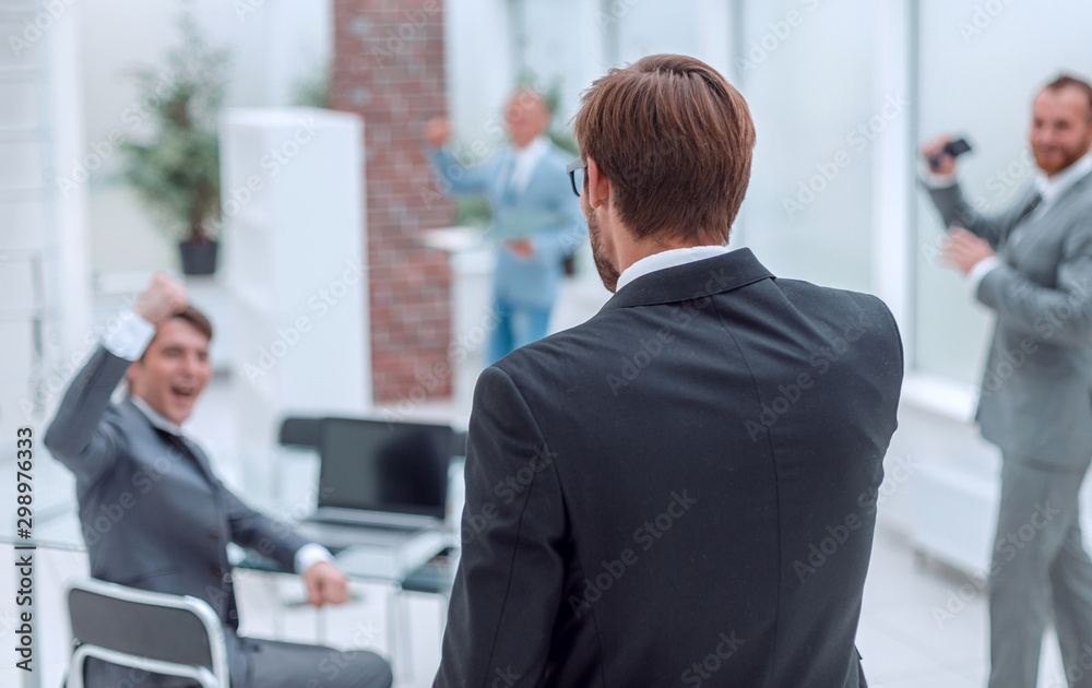 rear view. happy businessman standing in the office rear view. happy businessman standing in the office