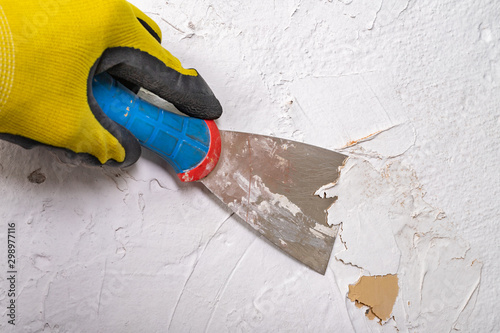 Konstfotografi Removing old paint from the wall with a metal spatula