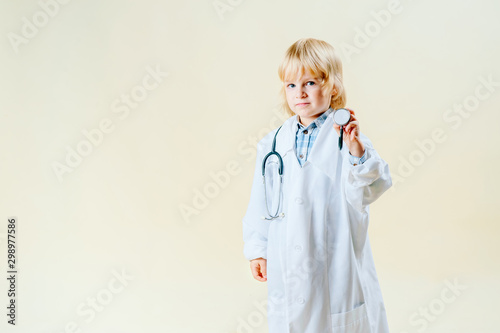 little blond blond boy in doctor clothes on a light isolated background photo
