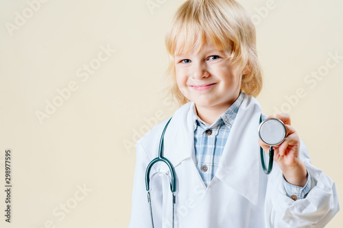 little blond blond boy in doctor clothes on a light isolated background photo