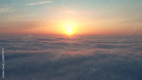 slow flight over the morning sky with pink clouds from which the sun rises.