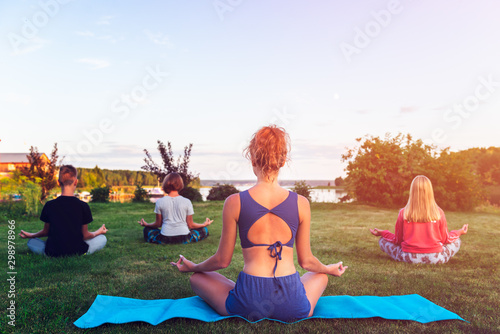 Young woman practicing yoga on the beach at sunset