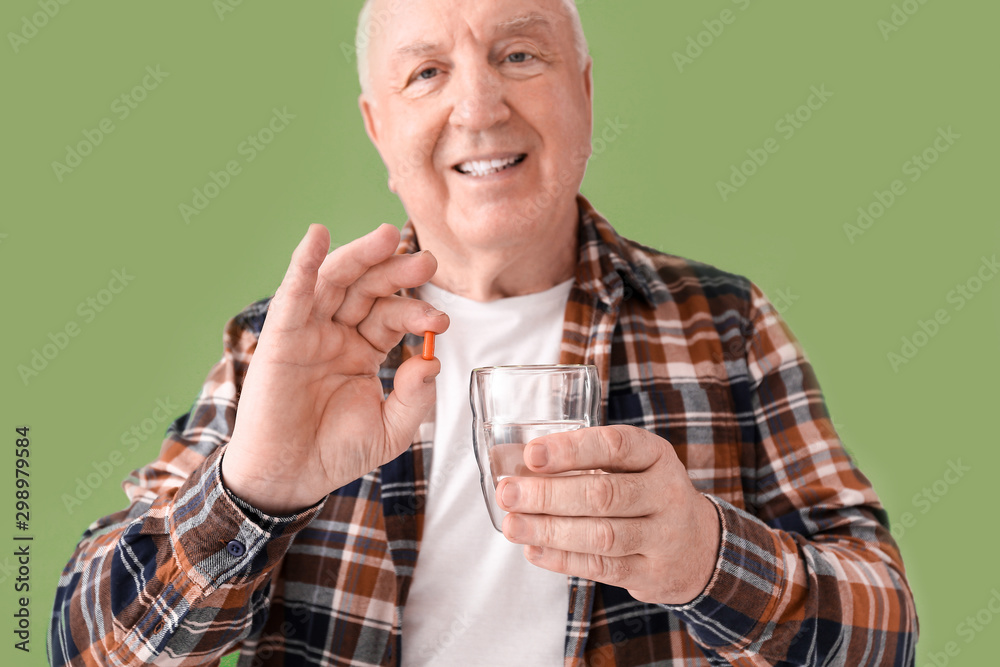 Elderly man taking medicine on color background Elderly man taking medicine on color background