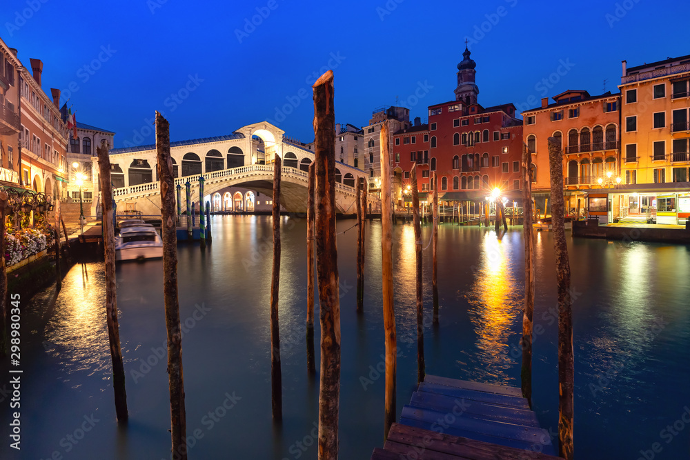Famous Rialto Bridge or Ponte di Rialto over the Grand Canal in Venice during evening blue hour, Italy.
