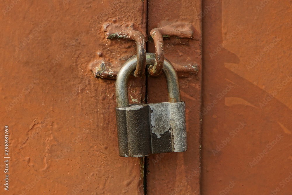 one gray big padlock on a brown iron wall one gray big padlock on a brown iron wall