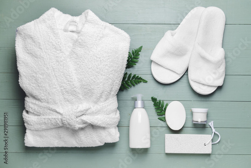 Clean bathrobe with spa supplies on wooden background photo