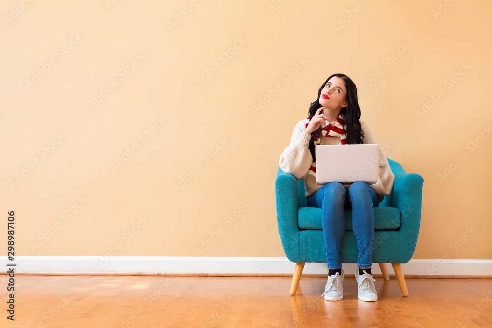 Young woman with a laptop computer in a thoughtful pose sitting in a chair Young woman with a laptop computer in a thoughtful pose sitting in a chair