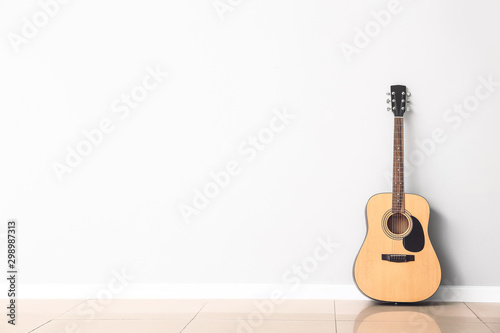 Fotografia Modern acoustic guitar near white wall