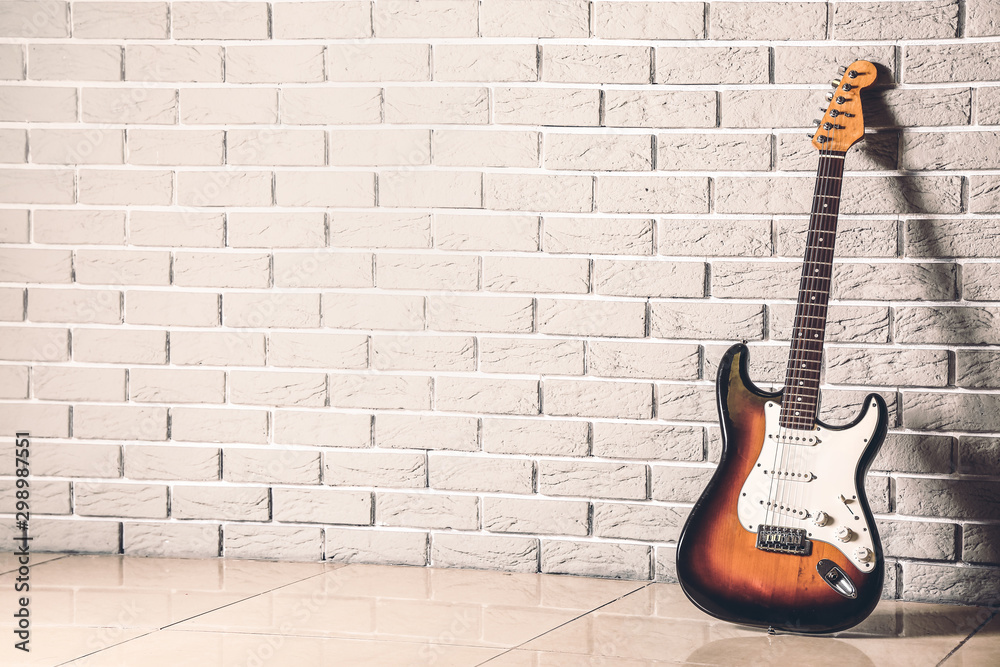 Modern bass guitar near brick wall - obrazy, fototapety, plakaty 