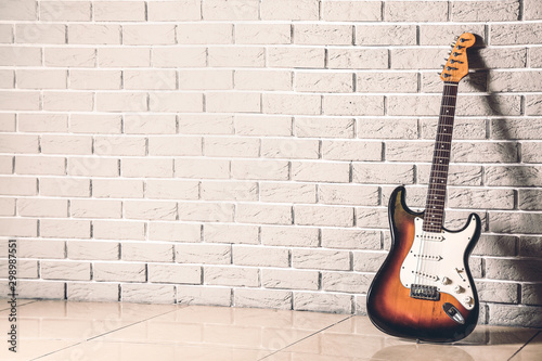 Modern bass guitar near brick wall