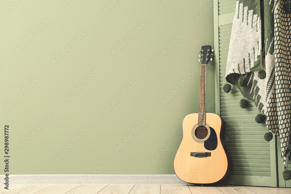 Fototapeta Nowoczesna gitara akustyczna i składany parawan w pobliżu kolorowej ściany