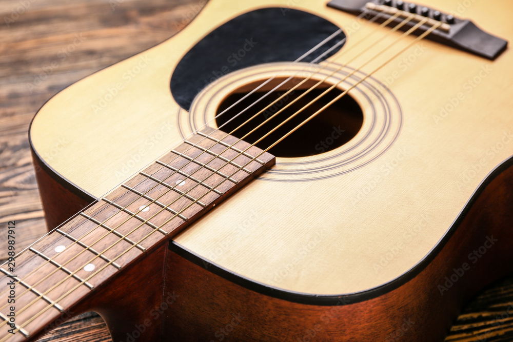 Modern acoustic guitar on wooden background, closeup