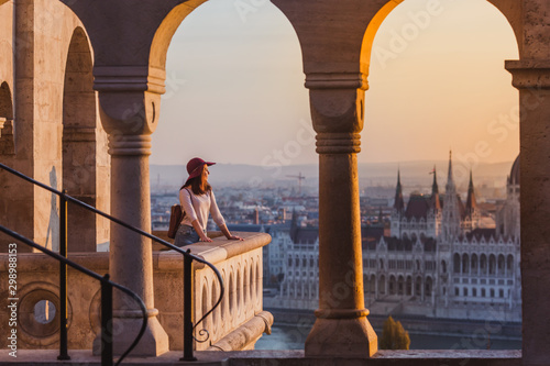 A happy young woman enjoying her trip to the Castle of Budapest in Hungary on the view point from Fisherman Bastion on sunrise.