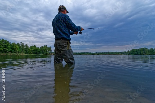 fisherman catching fish in the lake during cloudy day