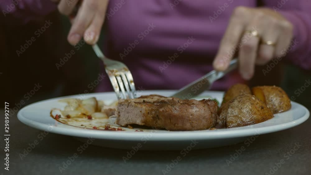 Steak cut with a knife on a plate by a caucasian woman in a luxury restaurant Steak cut with a knife on a plate by a caucasian woman in a luxury restaurant