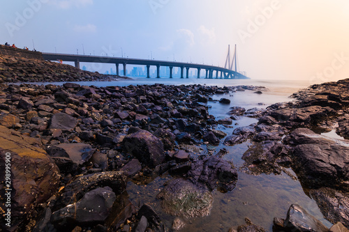 Minimalistic presentation of seascape Bandra worli sea link bridge in Mumbai  by the Arabian Ocean  Mumbai city downtown can be seen at the horizon. Smog in the air. Long exposure  smooth water. 