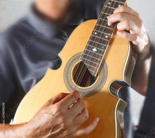 Close view of a Puerto Rican man with gray shirt playing a Cuatro, a national Puerto Rico musical string instrument.