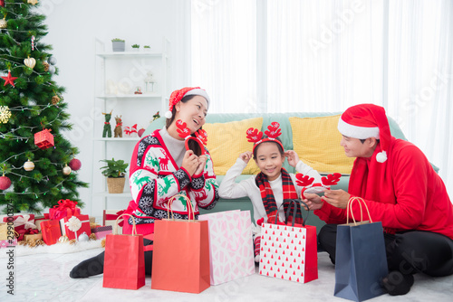 Happy asian family opening shopping bags and looking at goods that buy from shop in Christmas holiday discount sale. photo