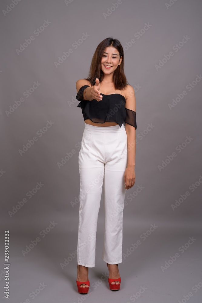 Young beautiful Asian woman against gray background Young beautiful Asian woman against gray background