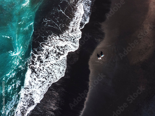 Happiness Couple enjoying on Black Sand Beach with white wave at Bali ,Indonesia