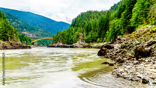 The mighty Fraser River, with the the arch shaped steel structure of the Alexandra Bridge on the Trans Canada Highway in the distance. Viewed from the upstream historic Second Alexandra Bridge photo