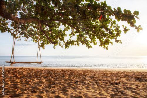 Landscape of the sea in the morning with tree and sand on the forgroung.Swings under the trees on the beach with sunset. photo