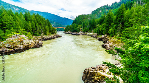 The mighty Fraser River, with the the arch shaped steel structure of the Alexandra Bridge on the Trans Canada Highway in the distance. Viewed from the upstream historic Second Alexandra Bridge photo