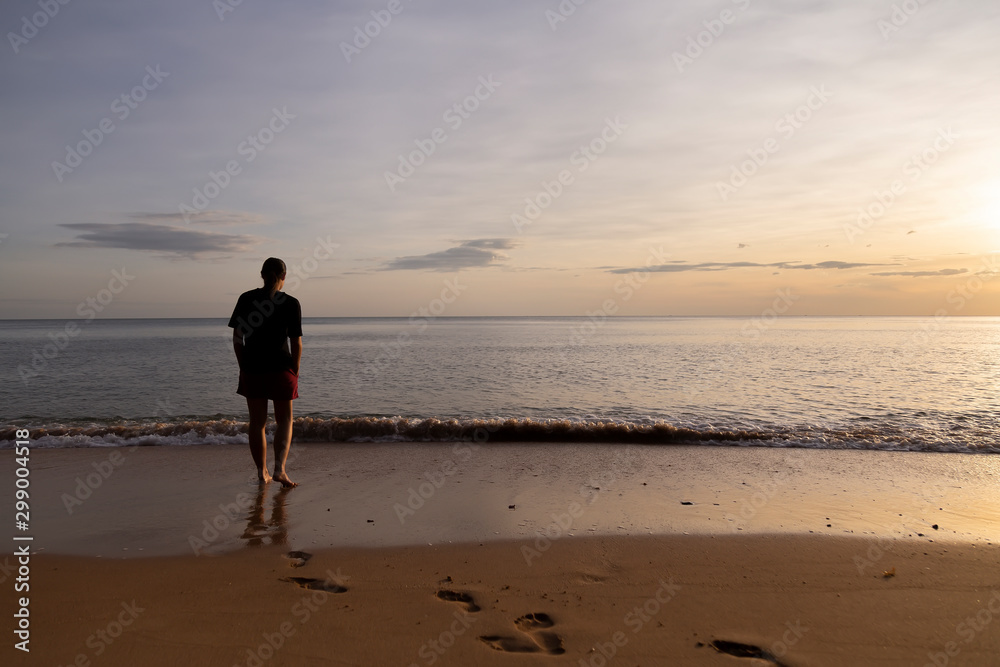 Romantic girl are looking the sun rise on the beach.Women are standing on the beach for looking the sunrise over the sea. There are feeling lonely for this  image.