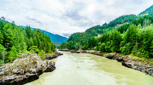 The mighty Fraser River, with the the arch shaped steel structure of the Alexandra Bridge on the Trans Canada Highway in the distance. Viewed from the upstream historic Second Alexandra Bridge photo