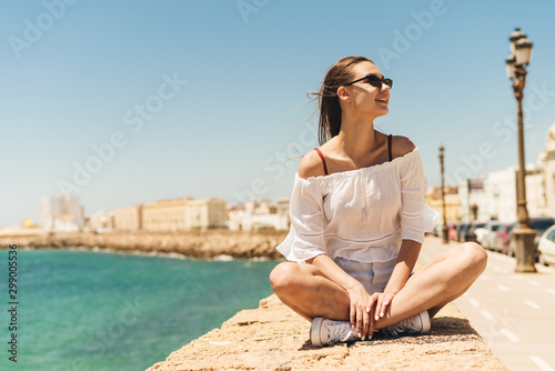 happy girl in lotus position on the background of the ocean and the city