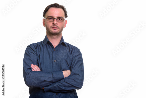 Studio shot of formal young man wearing eyeglasses with arms cro