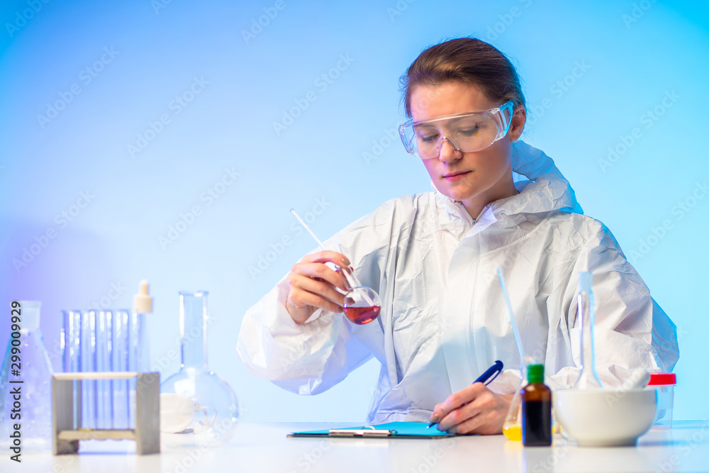 Work in a chemical laboratory. The girl holds a flask in her hands and records the result of the analysis. Laboratory experiments with chemical liquids. Research of samples of medicines. Pharmacology Work in a chemical laboratory. The girl holds a flask in her hands and records the result of the analysis. Laboratory experiments with chemical liquids. Research of samples of medicines. Pharmacology