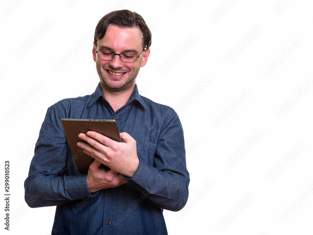 Studio shot of formal young happy man smiling while using digita Studio shot of formal young happy man smiling while using digita