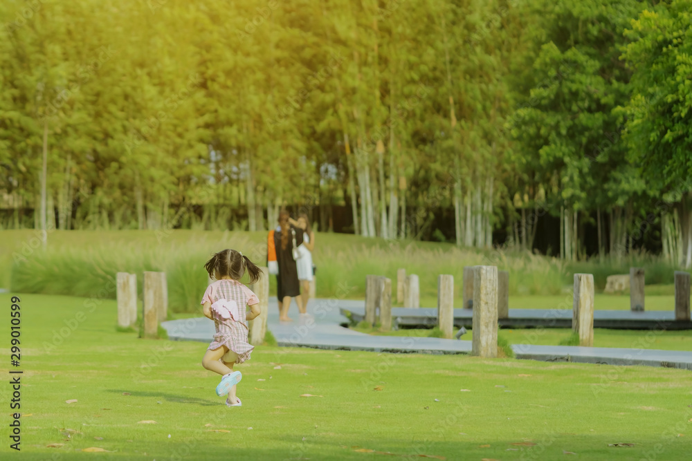 A little girl in a pink skirt enjoys a relaxing time playing on the green lawn at the public park in the evening. A little girl in a pink skirt enjoys a relaxing time playing on the green lawn at the public park in the evening.