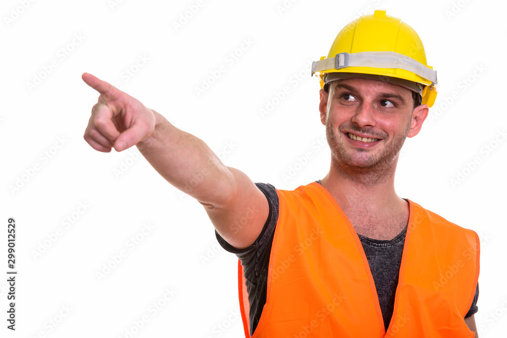 Studio shot of young happy man construction worker smiling while