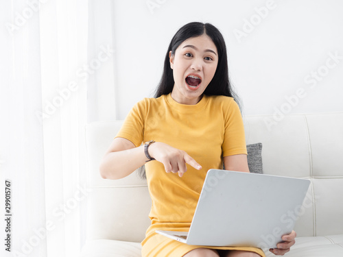 Asian woman in yellow dress using lapto at home, lifetyle concept. photo