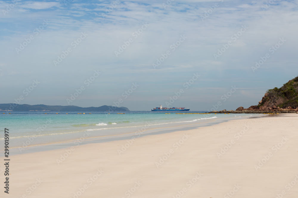 Container shipping by the sea. Sand beach tropical summer background. Cargo ship.