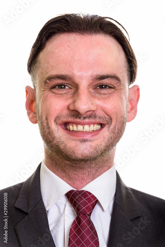 Face of young happy businessman in suit smiling