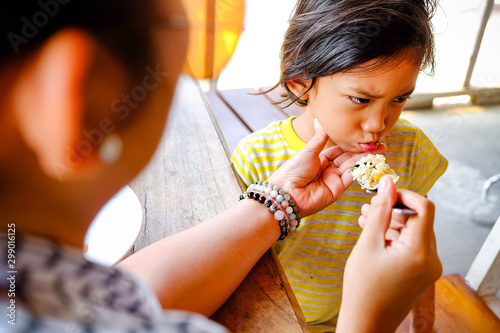 Asian Boy Showing Cranky Facial Expression while Being Feed Lunch Meals by His Mother in A Restaurant