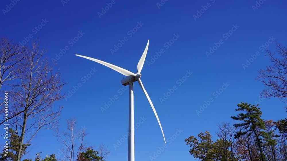 A wind turbine spins on a sunny, clear autumn day. A wind turbine spins on a sunny, clear autumn day.