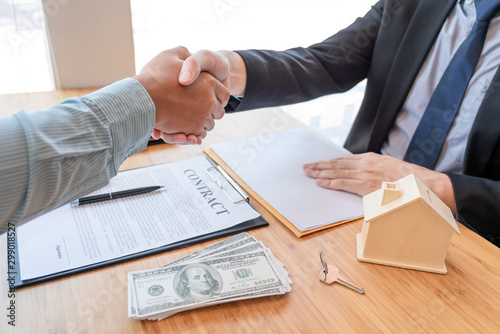 Estate agent shaking hands with customer after contract signature as successful agreement in real estate agency office. Concept of housing purchase and insurance
