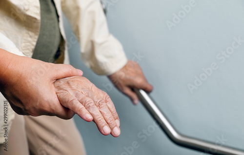 Elderly woman holding on handrail with caregiver photo